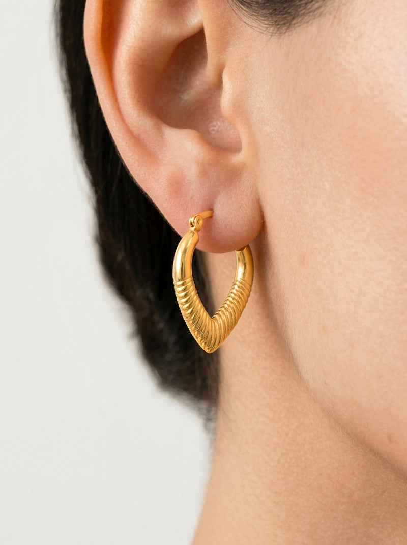 Curvy Gold heart hoop earring worn by a person with a neutral background