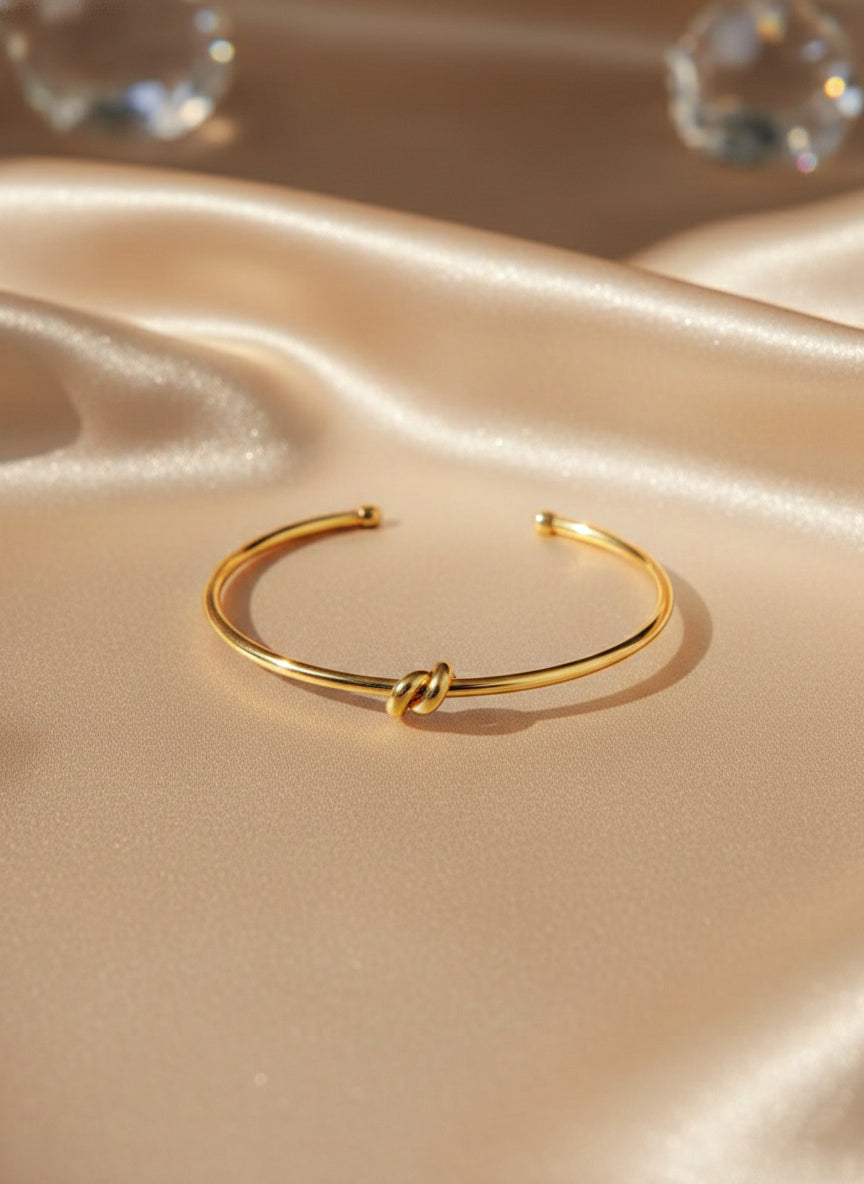 close up of 18k gold bracelet with knot pattern on beige surface