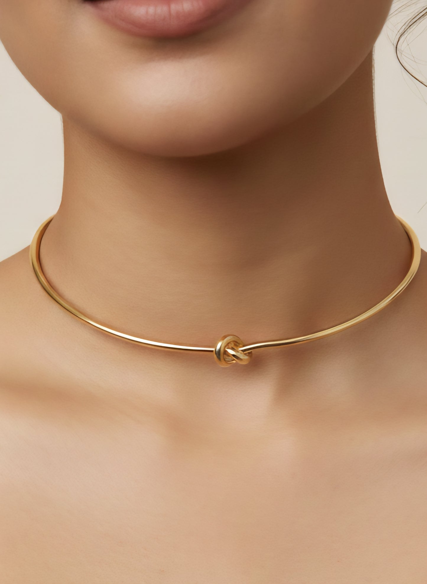close up of stainless steel Gold knot necklace on a model with a neutral background