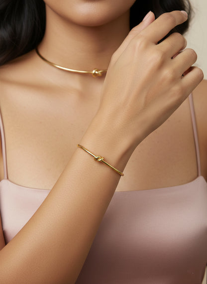 close up of set of stainless steel gold choker and bracelet with knot designs worn by model 