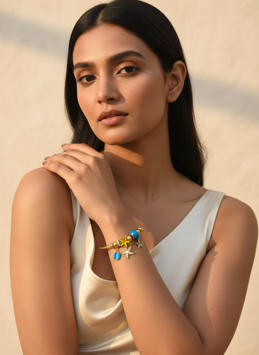 Woman wearing a stainless steel ocean theme star bracelet with colorful charms against a beige background
