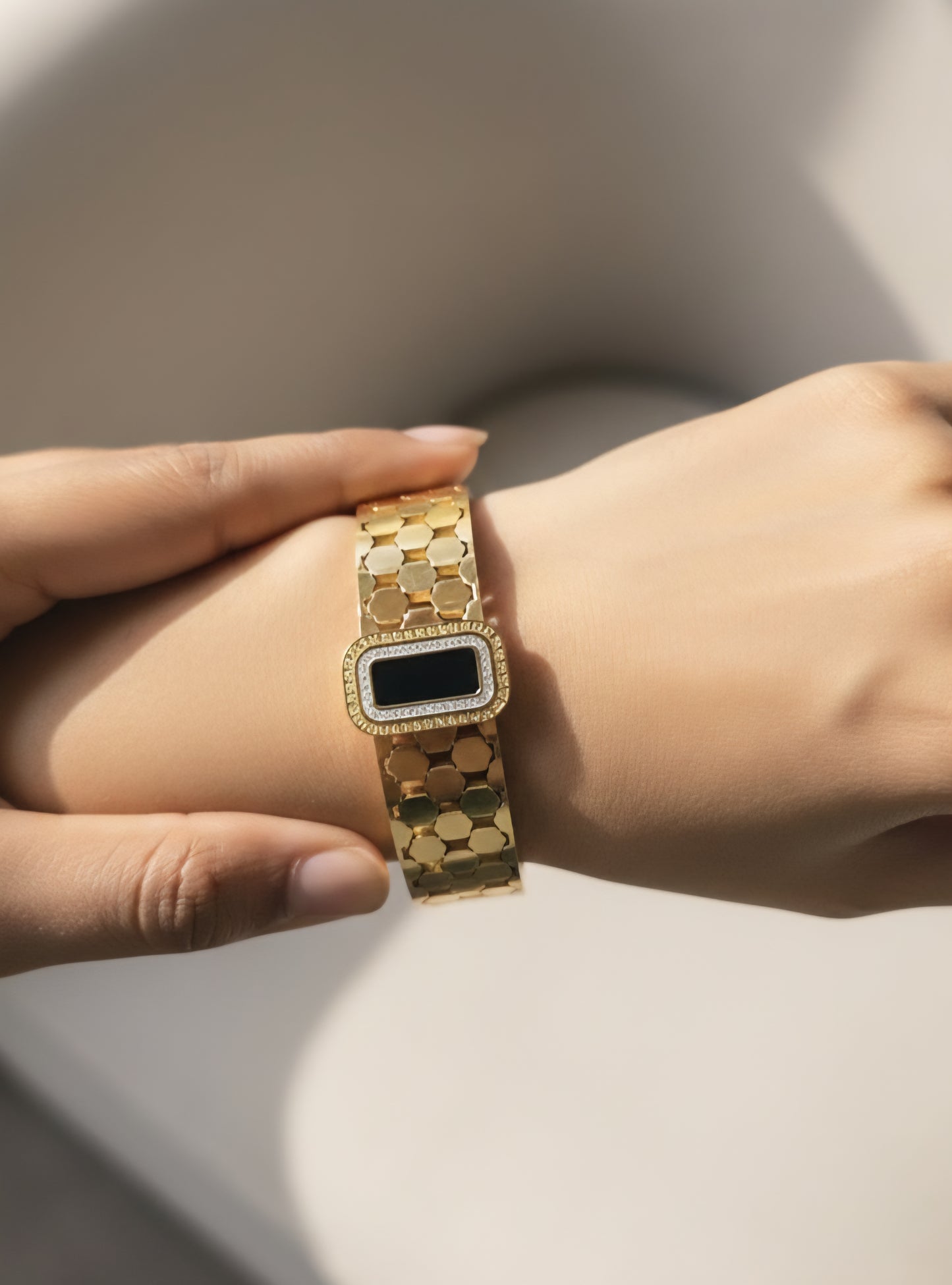 18k gold stainless steel signature black bracelet on wrist with neutral background